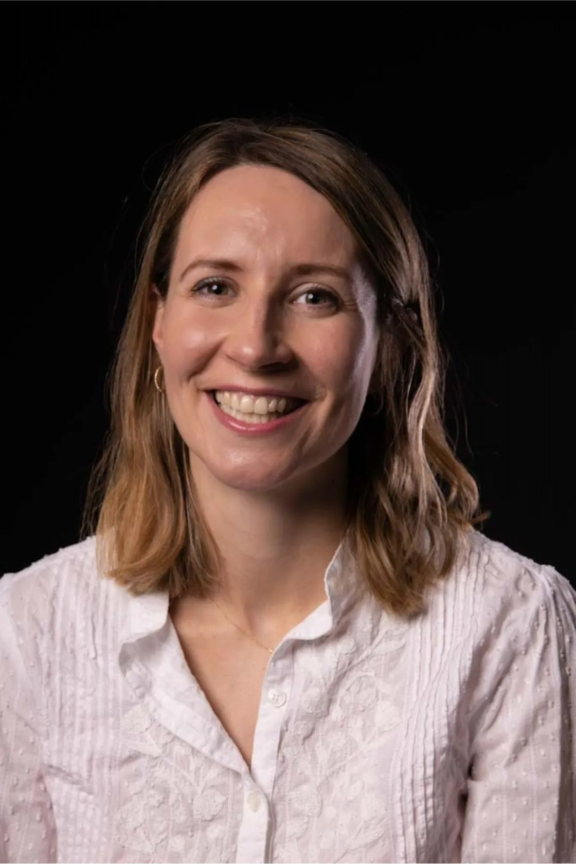 Amandine Partas, Trade marketing project manager avec 8 ans d'exp&eacute;rience en train de s'&eacute;venter avec un chapeau, photo sur fond noir.